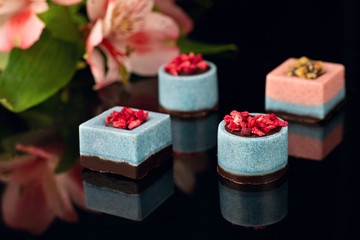 Chocolate candies without sugar on black acrylic. Raw vegan chocolate candies. Lactose free candies. Gluten free candies. Without artificial dyes chocolate.