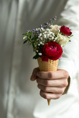 Beautiful bouquet in man's hands on a background of gray wall. Flowers art design. Man in white...