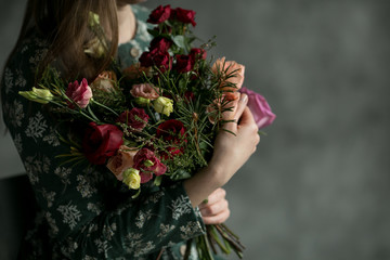 The young  woman in the green dress with beautiful bouquet from roses. Hands with amazing flowers.