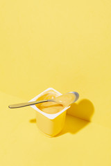 Banana and vanilla pudding or yogurt plastic cup on pastel yellow background.Minimal abstract food concept
