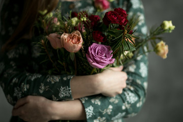 The young  woman in the green dress with beautiful bouquet from roses. Hands with amazing flowers.