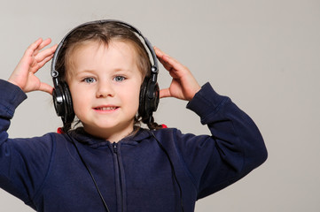 Smiling little girl with head phones on studio.