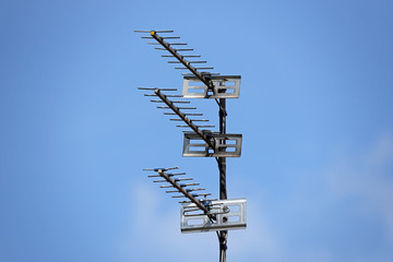Three TV Aerials mounted on a single pole with a blue sky background