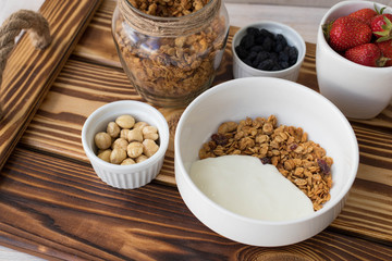 Dry breakfast, oat with nuts, yogurt and strawberries on a wooden table