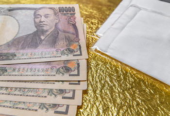 tokyo, japan - may 20 2020: Cloth masks and 100,000 yen in cash sent by the Japanese govt of Abe Shinzo to fight COVID-19 on a golden paper.