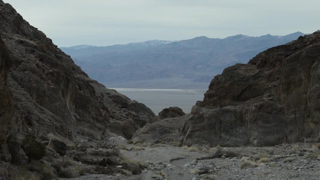 A male hiker exits the mouth of Fall Canyon in Death Valley National Park in California. The Panamint mountain range is seen in the distance.