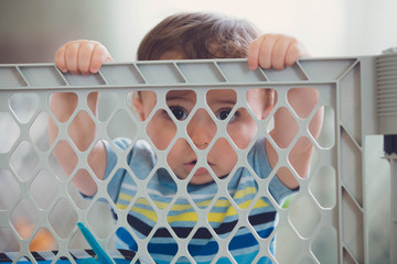 little happy boy playing in the crib looking out 