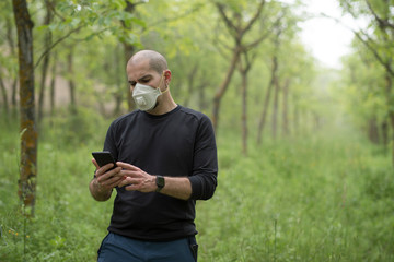 Man in forest with telephone an medical mask