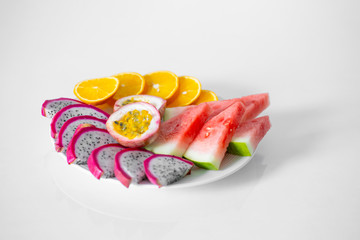 White plate of sliced fruit. Fresh fruits and vitamins. Still life colored summer fruits.