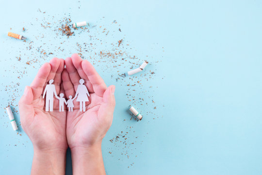 Hand protect family from cigarette on light blue background. Stop smoking for your family. World No Tobacco Day concept. Copy space for advertisers.