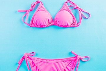 Sexy pink bikini  on light blue background. Top view flat lay, hipster beach clothes, chic...