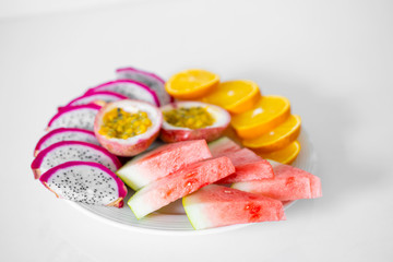 White plate of sliced fruit. Fresh fruits and vitamins. Still life colored summer fruits.