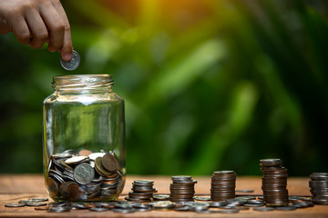 Coins a men's hand  placed and sorted coins on a wooden board.