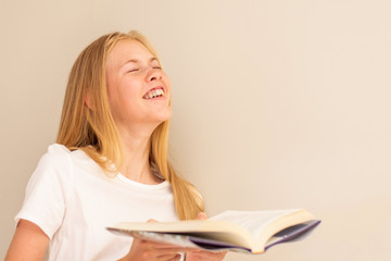 Teenage girl laughing with the book in her hand. Love to read. Selective focus