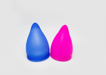 Two colorful, pink and blue sizes of menstural cups from medical high quality silicone, 20 and 30 ml capacity, for safe menstual female period, ecological, zero waste device at isolated background