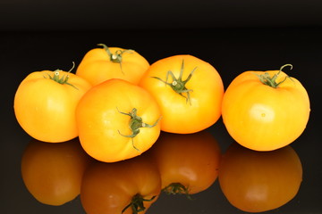 Ripe juicy yellow tomato on a black background.