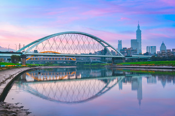 Obraz premium Rainbow Bridge, landscape view of long bridge lies across the Keelung river with colorful sunset sky at Songshan district, Taipei City, Taiwan