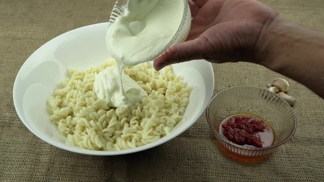 Turkish stile spiral pasta is served with yogurt and tomato sauce
