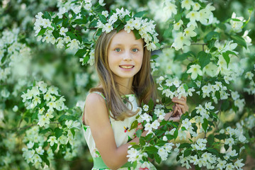 Portrait of a beautiful young long-haired girl. Adorable child having fun in blossom cherry garden on beautiful spring day.