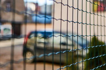 Car behind the fence net. Parking, fine area.