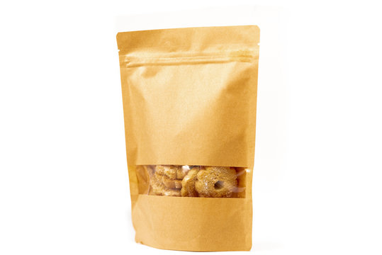 brown craft food packaging in paper, plain doypack standup bag filled with biscuits with window and zipper on white background