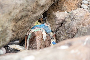 garbage on the beach among the rocks. stop plastic