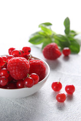Fresh berries: raspberries and red currants in white bowl with mint on a white  background. Background image, copy space