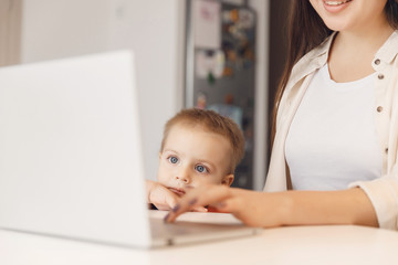 Business mom is using online work laptop, woman spending time with her boy baby home