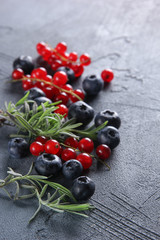 Fresh berries: blueberries, red currants and herbs on a dark grey background. Background image, copy space