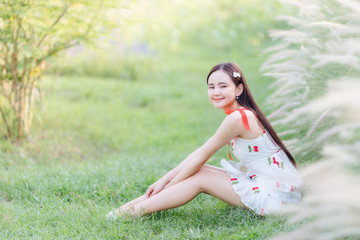 Naklejka na ściany i meble Beautiful Asian woman wear white dress siting on lawn in garden.