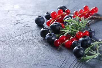 Fresh berries: blueberries, red currants and herbs on a dark grey background. Background image, copy space
