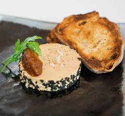 Duck liver pate Foie gras with jam and herbs, rustic piece of bread, crispy tasted bread, on a stone board.