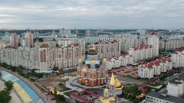 Aerial photography. Orthodox Christian Church on the Obolonskaya embankment in the spring in Kiev. Many houses built along the Dnieper Bay. Drone.