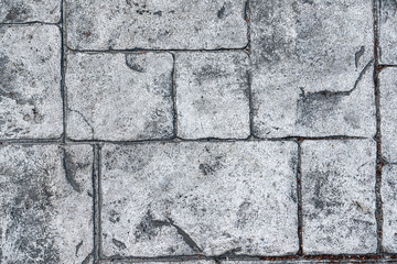 the background is a textured gray stone. Old pavement close-up view from above, blocks of stones