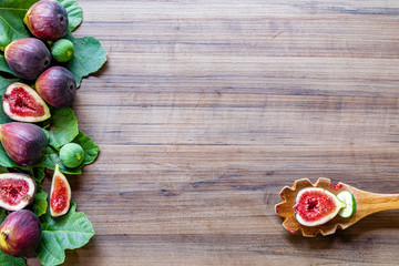 Fototapeta na wymiar Top view of figs, green leaves on rustic wooden background