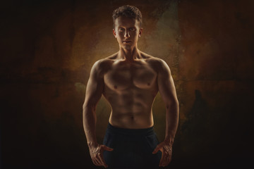 Fototapeta na wymiar Athletic man posing. Photo of man with perfect physique on grunge background. Strength and motivation.