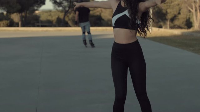 Pretty skater girl skating on roller skates at sunset