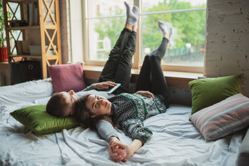 Lying down, lovely. Quarantine lockdown, stay home concept - young beautiful caucasian couple enjoying new lifestyle during coronavirus worldwide health emergency. Happiness, togetherness, healthcare.