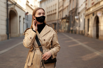 Fototapeta premium Woman wearing trendy fashion outfit during quarantine of coronavirus outbreak. Model dressed protective stylish handmade face mask. Tourist walkin on empty street. Woman with fashion protective mask.