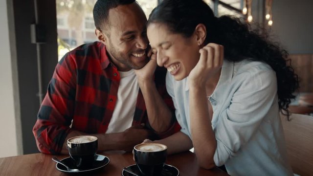 smiling african man and woman sitting at a cafe and talking. Happy young couple on a date at coffee shop.
