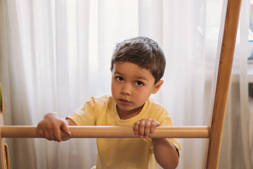 adorable kid looking at camera while touching ladder of home gym