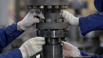 Oil and Gas Wellhead tree equipment production plant. Worker assembles of wellhead fitting. Modern tendencies of machine engineering. Equipment for wellhead conncetion of oil and gas wells.