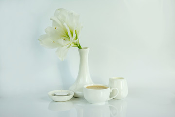 Obraz na płótnie Canvas Coffee, milk, a flower, a candle are in a white bowl on a white background.