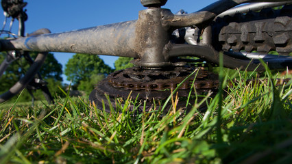 Underside of muddy used bike lying on grass against blue sky