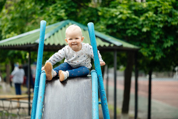 Fototapeta na wymiar child on the street plays himself on a slide. Walking in the fresh air.