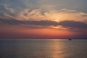 Sunset at the sea. Amazing clouds and a lonely boat. Halkidiki, Greece.