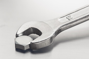 Wrench tightens  bolt in steel billet. Spanner, bolt, screw and nuts.