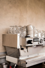 .metal coffee machine with cups upstairs against a concrete wall