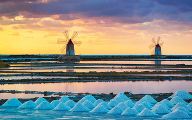 Sunset at Windmills in salt evoporation pond in Marsala Sicily reflex - obrazy, fototapety, plakaty