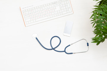 Keyboard, phone and stethoscope on a wooden background. The view from the top. Doctor's workplace